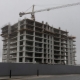 A residential tower under construction with a crane, seen from street level.