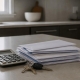 A stack of invoices, a calculator and keys on a kitchen island.