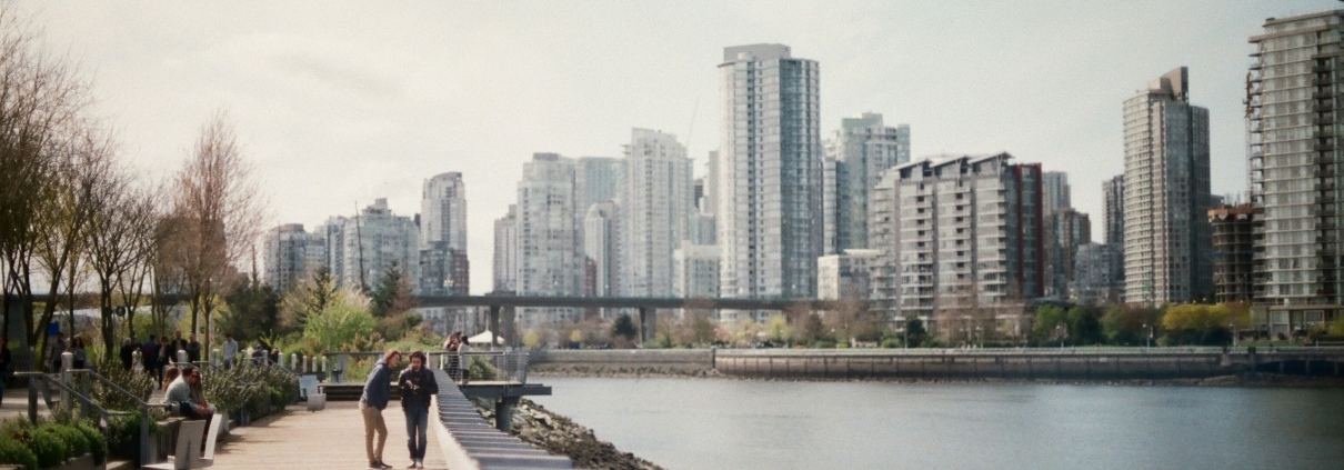 Two people walking out along a wooden pier over calm water.