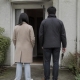 Two people seen from behind at the open front door of a townhouse.