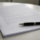 An agreement on a table with a pen resting on the signature line.