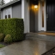A tidy house entrance with a swept walkway, trimmed hedge and new doormat.