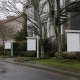 Blank real estate sign posts outside townhouses on a wet autumn street.