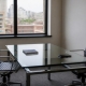 A small meeting room with a glass table, two empty chairs and a notebook.