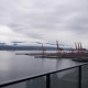 A residential balcony overlooking a working waterfront with distant cranes.