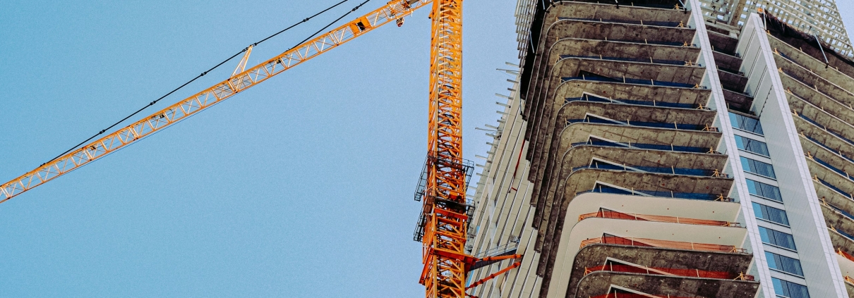 A tower crane above an apartment building under construction.