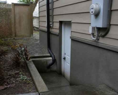 A separate basement suite entrance with its own door and concrete steps.